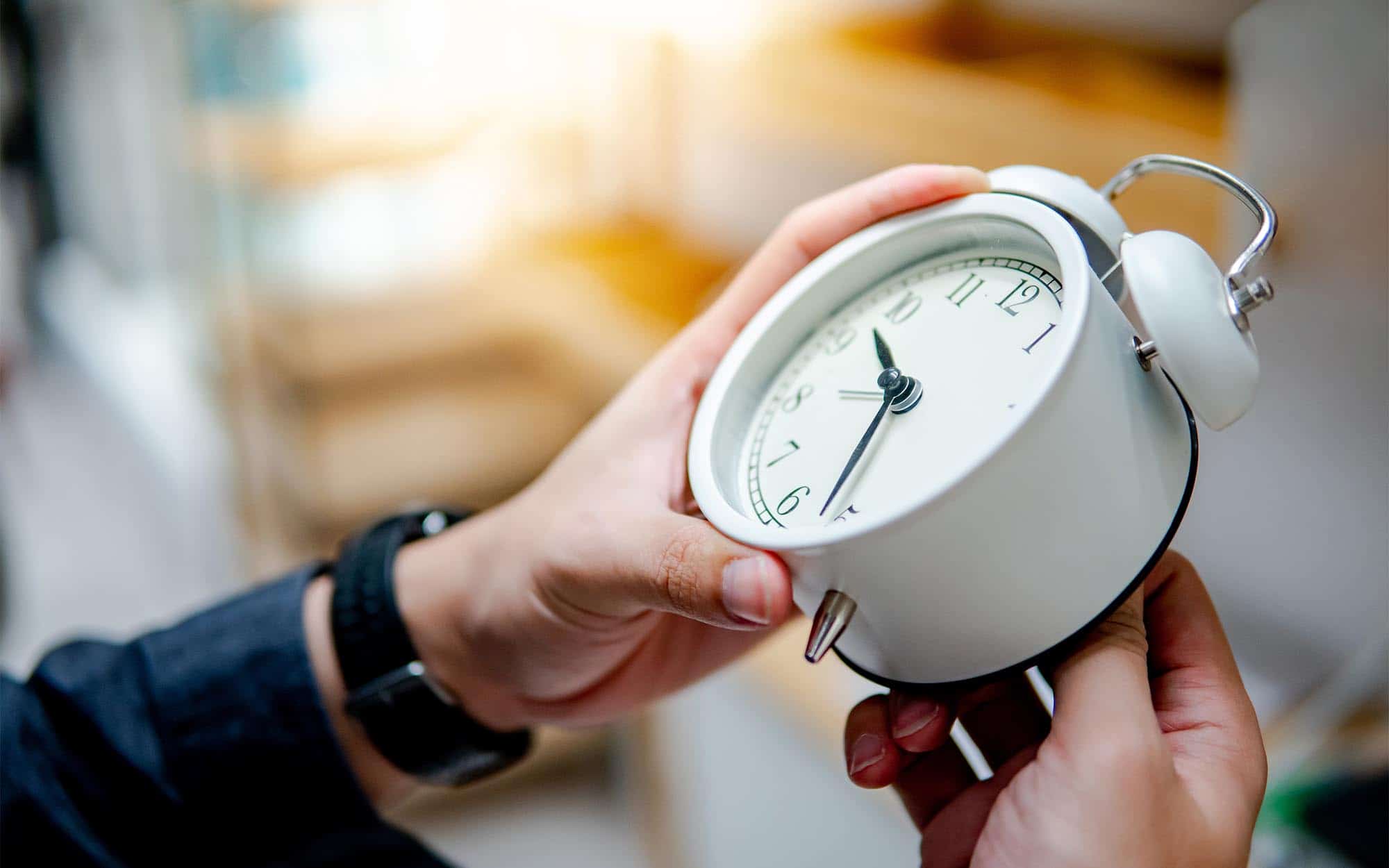 Person setting clock back for daylight saving